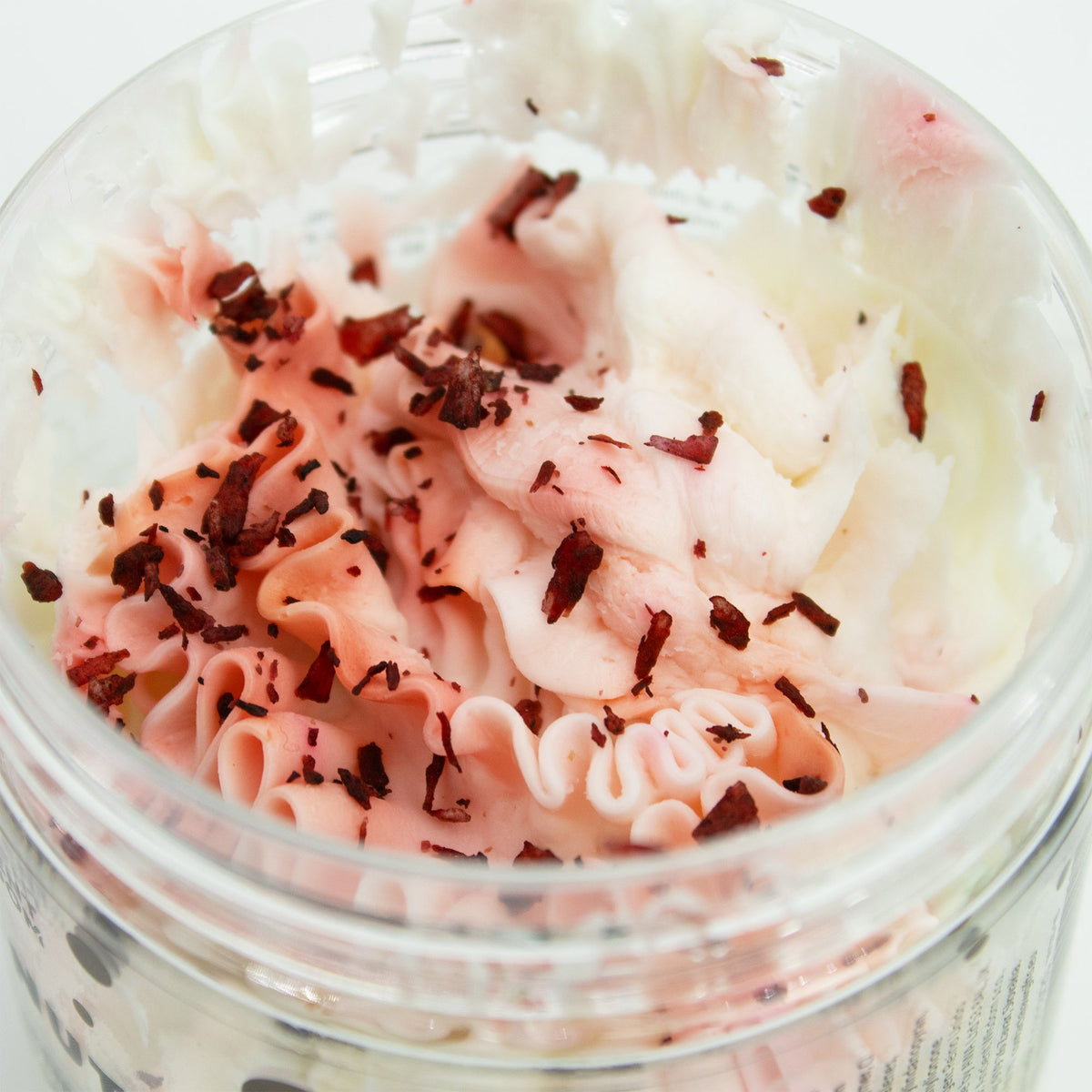 Close-up of a container of pink whipped soap with shavings