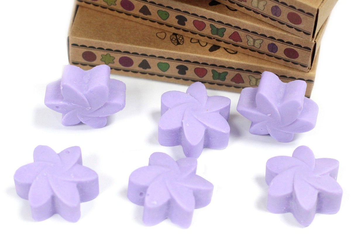 Purple flower-shaped objects on a white surface with a cardboard box in the background.