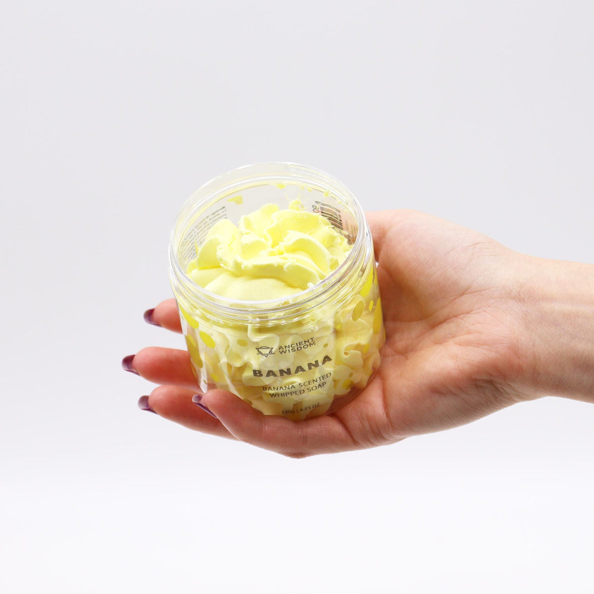 Hand holding a container of banana-flavored product with a white background