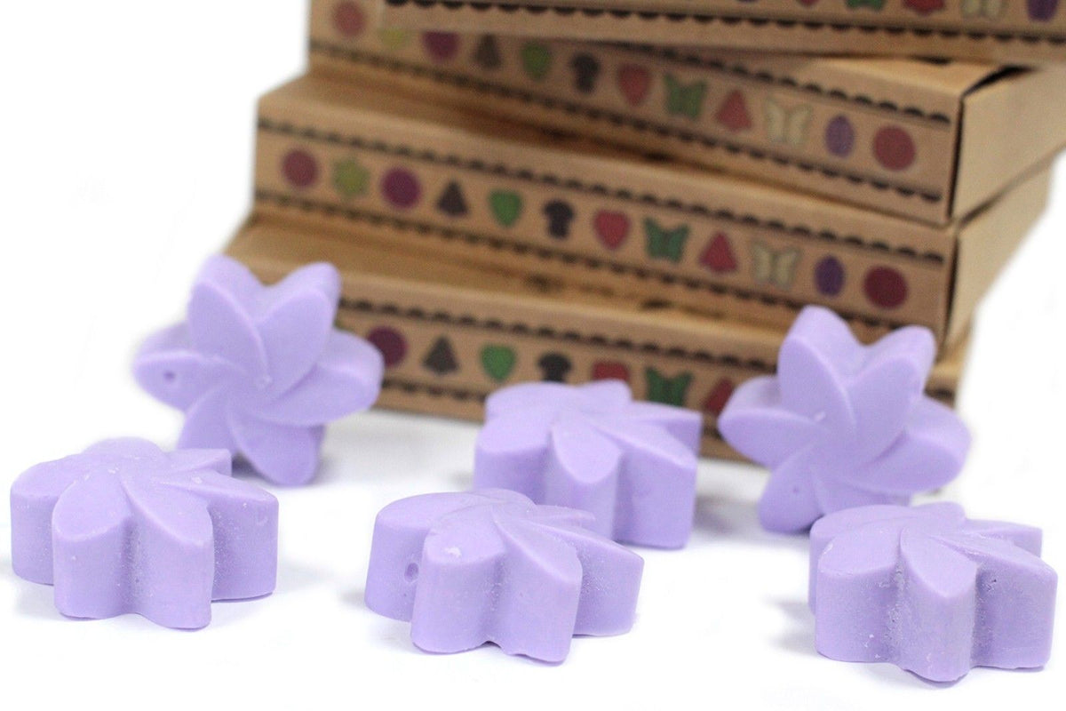 Purple butterfly-shaped wax melts on a white surface with a decorative box in the background.