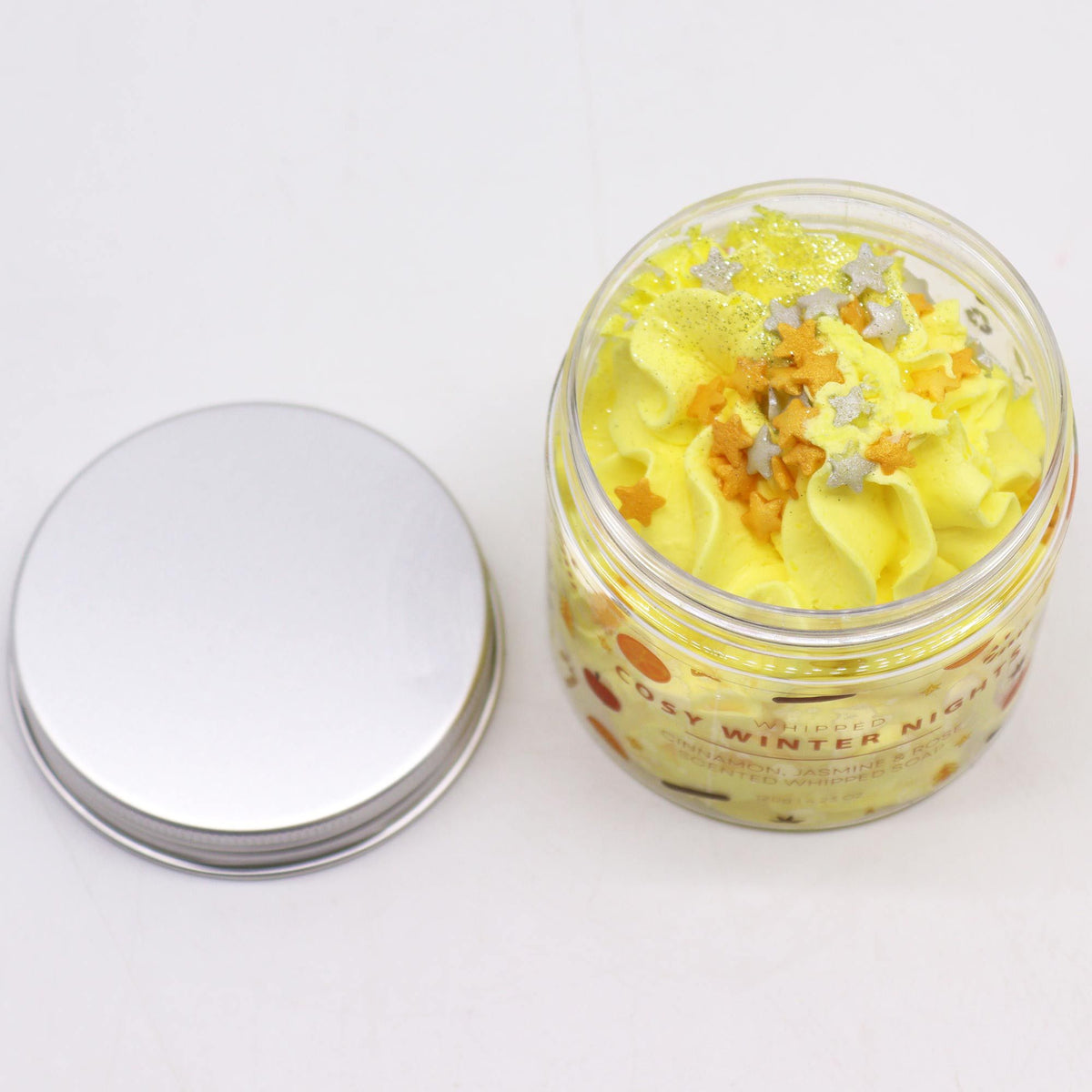 Jar of yellow whipped soap with decorative elements on a white background