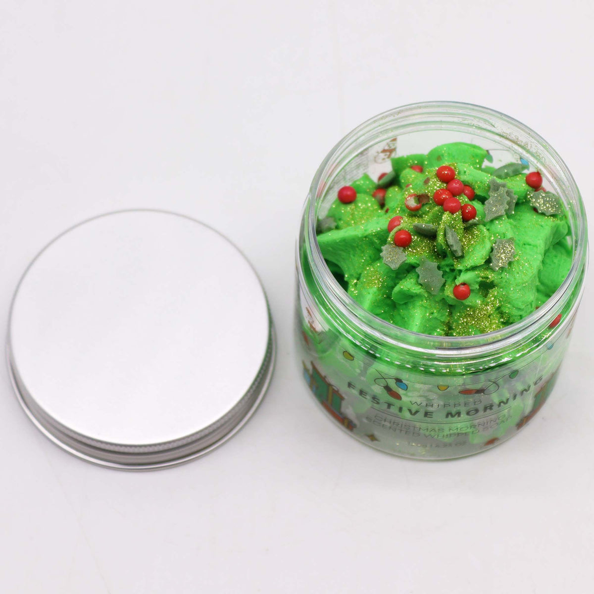 Jar of green whipped soap with red and gold decorations on a white background