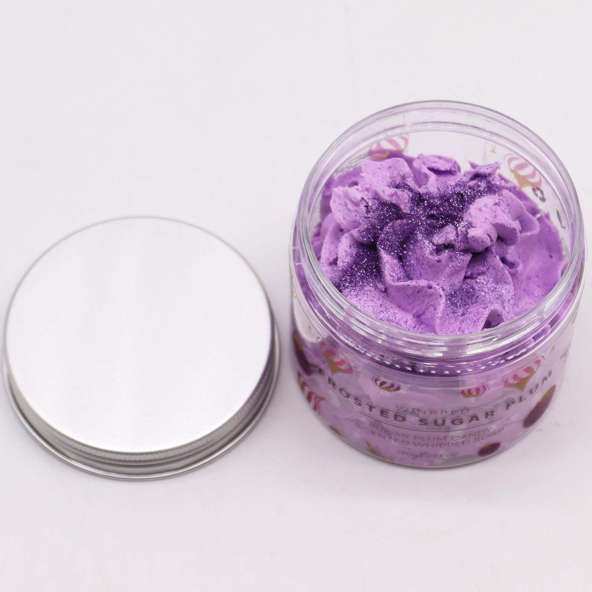 Jar of purple whipped soap with a silver lid on a white background