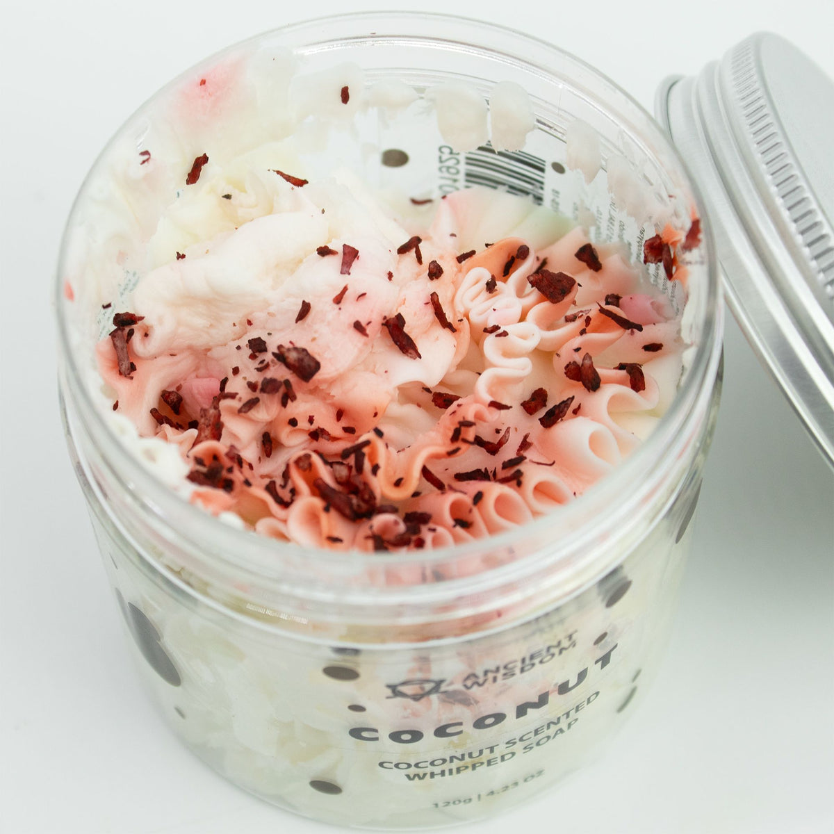 Jar of coconut-scented whipped soap with pink and red specks on a white background